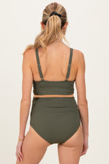 woman wearing a dark green ribbed maternity bikini top and high-waisted bottoms, showing a smooth back view