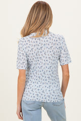 woman wearing a light blue short sleeve maternity top with floral print and back view visible