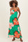 woman wearing a green floral maternity maxi dress with pockets and holding her baby bump