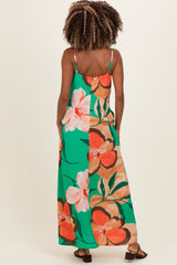 woman wearing a floral green and orange maternity maxi dress with spaghetti straps, showing her back and long hair