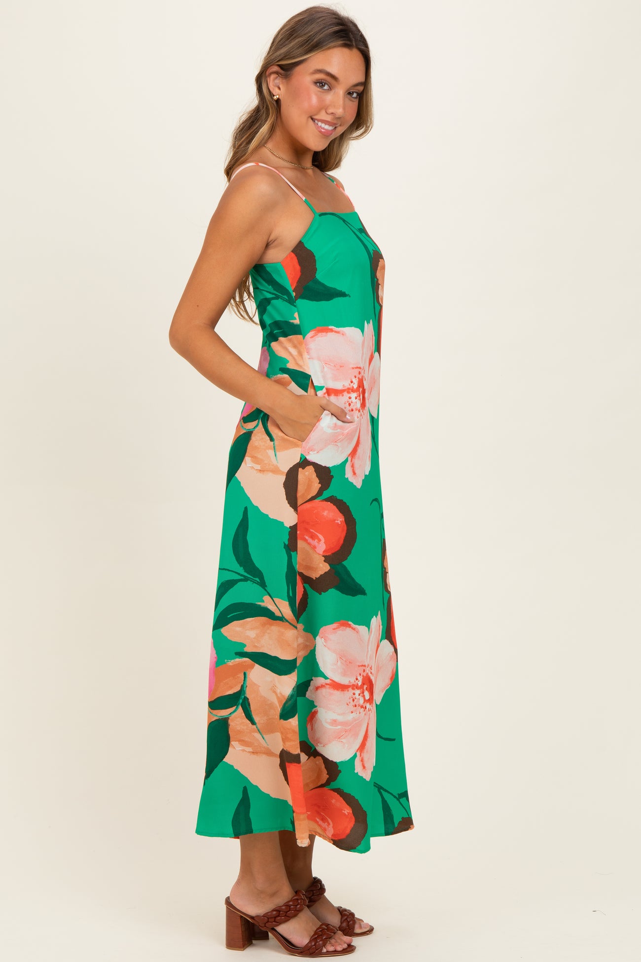 woman wearing a green floral maxi dress with spaghetti straps and side pockets