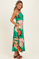 woman wearing a green floral maxi dress with spaghetti straps and side pockets
