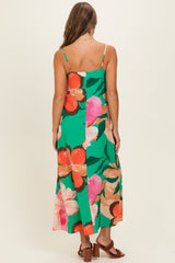 woman wearing a green floral maxi dress with thin straps and a flowy silhouette, showing the back view