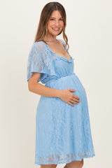 woman wearing a light blue lace maternity dress with short sleeves and holding her baby bump