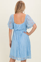 woman wearing a light blue lace dress with short puff sleeves and a cinched waist, showing a low back detail