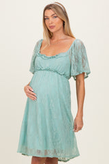 woman wearing a mint green lace maternity dress with short sleeves and holding her baby bump