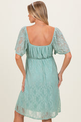 woman wearing a mint green lace maternity dress with short sleeves and a cinched waist, showing a baby bump from the back