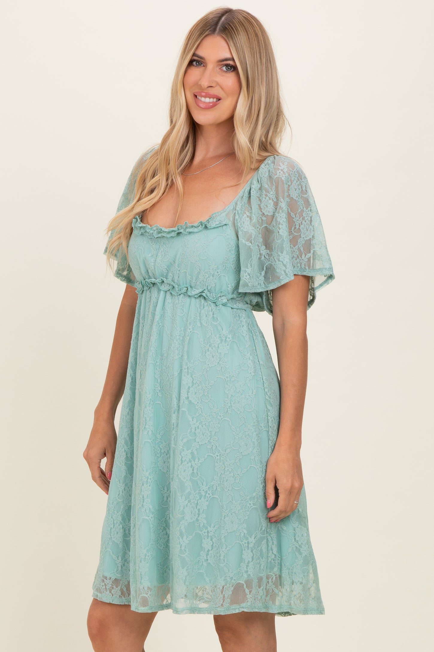 woman wearing a mint green lace short dress with flutter sleeves and a smocked waist