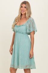 woman wearing a mint green lace short dress with flutter sleeves and a smocked waist