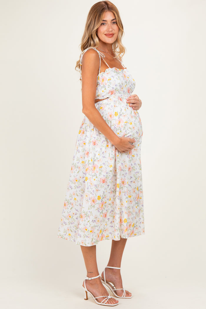 woman wearing a floral maternity sundress and holding her baby bump
