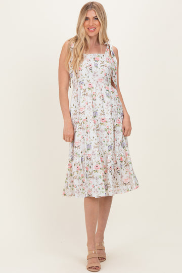 woman wearing a white floral midi dress with spaghetti straps and a tiered skirt