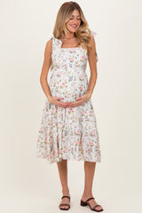 woman wearing a floral print maternity dress with ruffle straps and holding her baby bump
