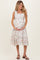 woman wearing a floral print maternity dress with ruffle straps and holding her baby bump