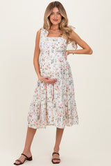 woman wearing a floral maternity dress with tie straps and holding her baby bump