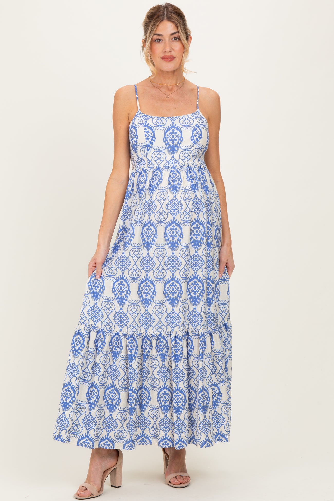 woman wearing a blue and white patterned maternity maxi dress with spaghetti straps and a ruffled hem