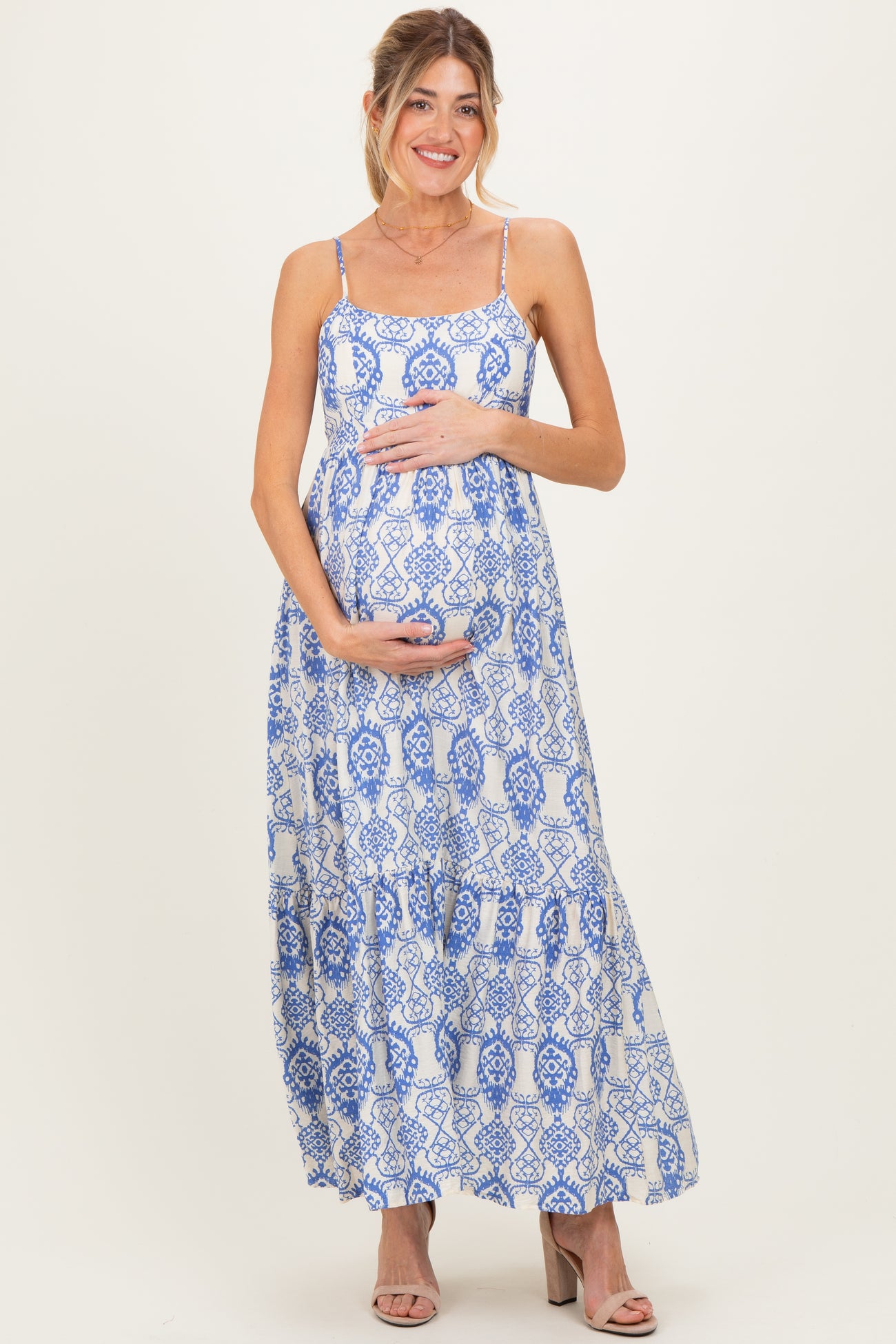 woman wearing a blue and white patterned maternity maxi dress and holding her baby bump