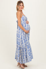 woman wearing a blue and white patterned maternity maxi dress and holding her baby bump