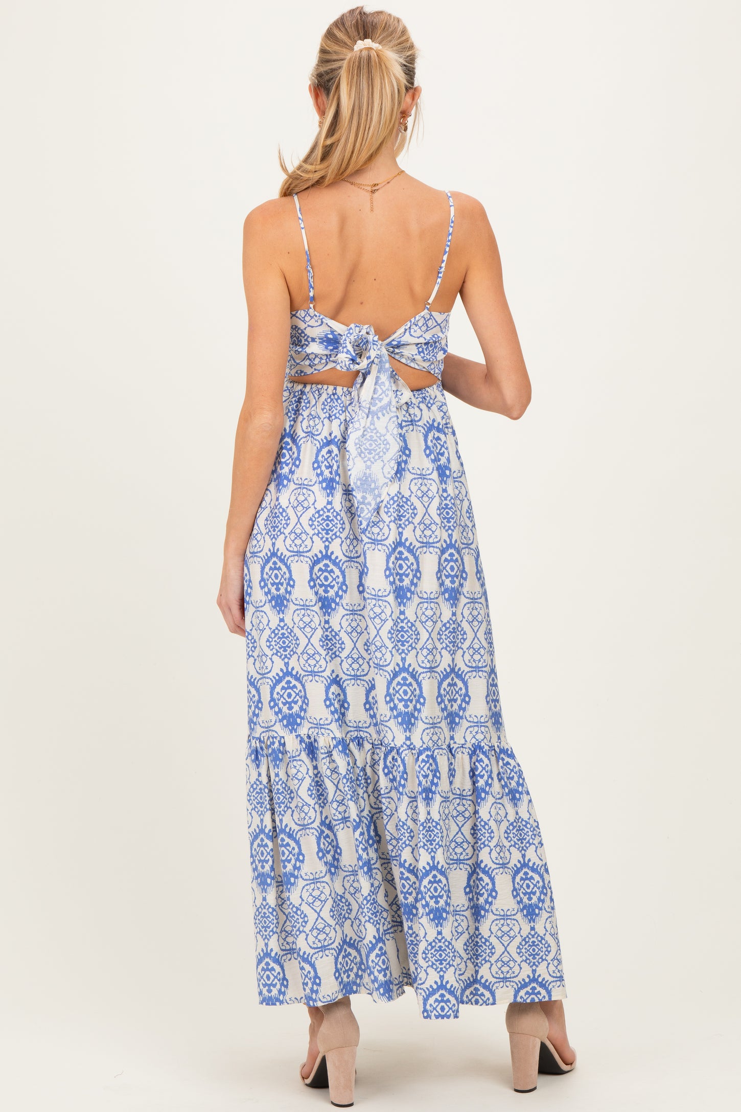 woman wearing a blue and white patterned maternity maxi dress with adjustable spaghetti straps and a tie-back detail