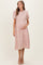 woman wearing a dusty pink lace maternity dress with short puff sleeves and a baby bump
