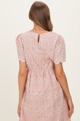 woman wearing a pink maternity dress with puff sleeves and lace detailing, showing the back view