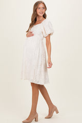 woman wearing a light pink maternity dress with puff sleeves and a fitted bodice, holding her baby bump