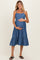 woman wearing a blue tiered maternity dress and cradling her baby bump