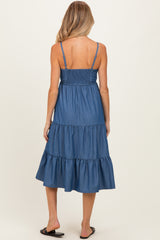 woman wearing a blue chambray maternity dress with a smocked top and tiered skirt, showing her back