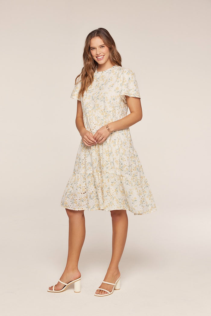 woman wearing a light yellow floral fit-and-flare dress with short sleeves and tiered skirt