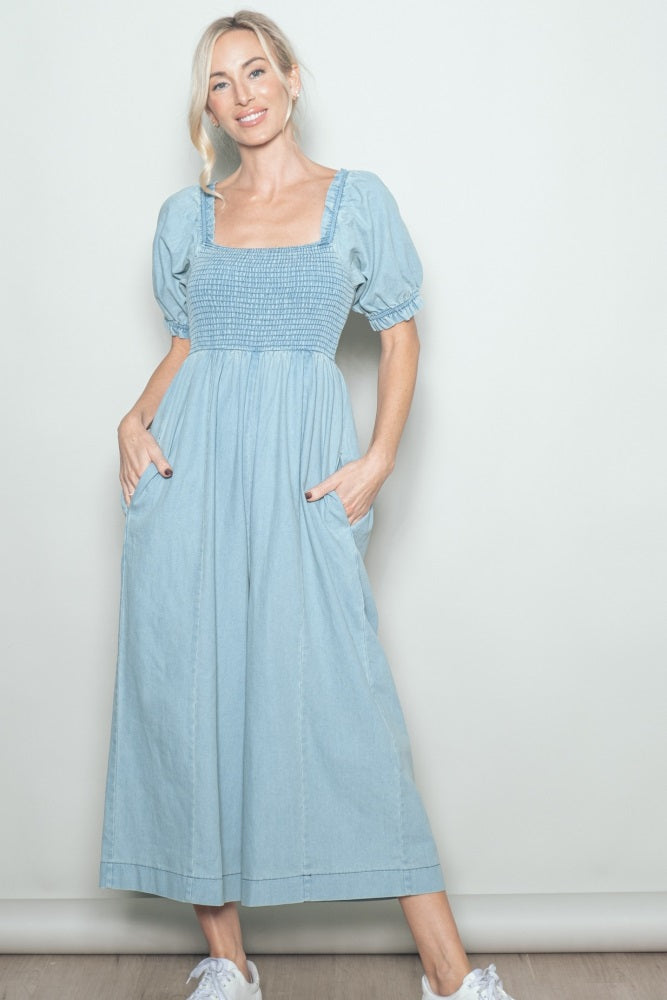 woman wearing a light blue smocked maxi dress with puff sleeves and pockets, styled with white sneakers