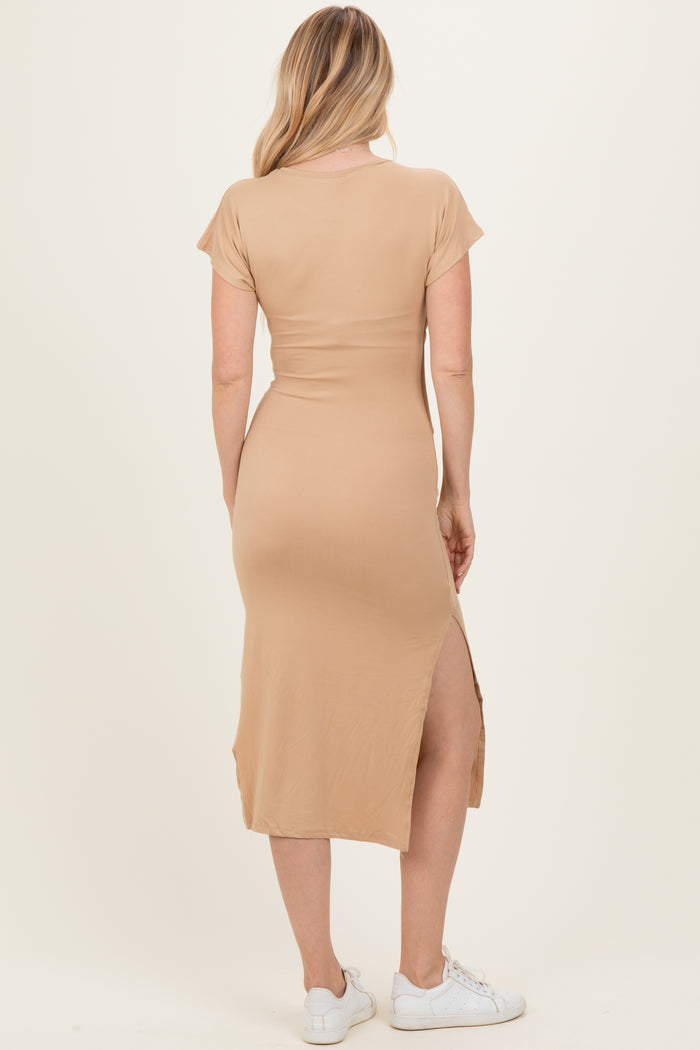woman wearing a tan short sleeve maxi dress with a side slit, showing the back view and styled with white sneakers