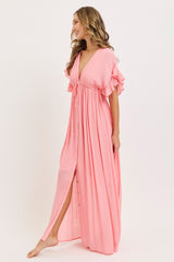 woman wearing a pink maxi dress with flutter sleeves and a cinched waist, featuring button details down the front