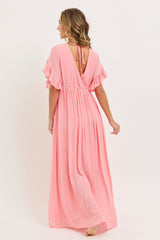 woman wearing a long pink maxi dress with ruffled sleeves and an open back detail