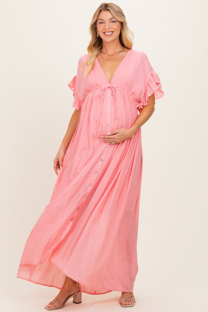 woman wearing a pink maternity maxi dress with ruffled sleeves and a button-down front, holding her baby bump