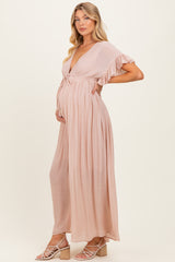 woman wearing a light pink maternity maxi dress with ruffled sleeves and a visible baby bump