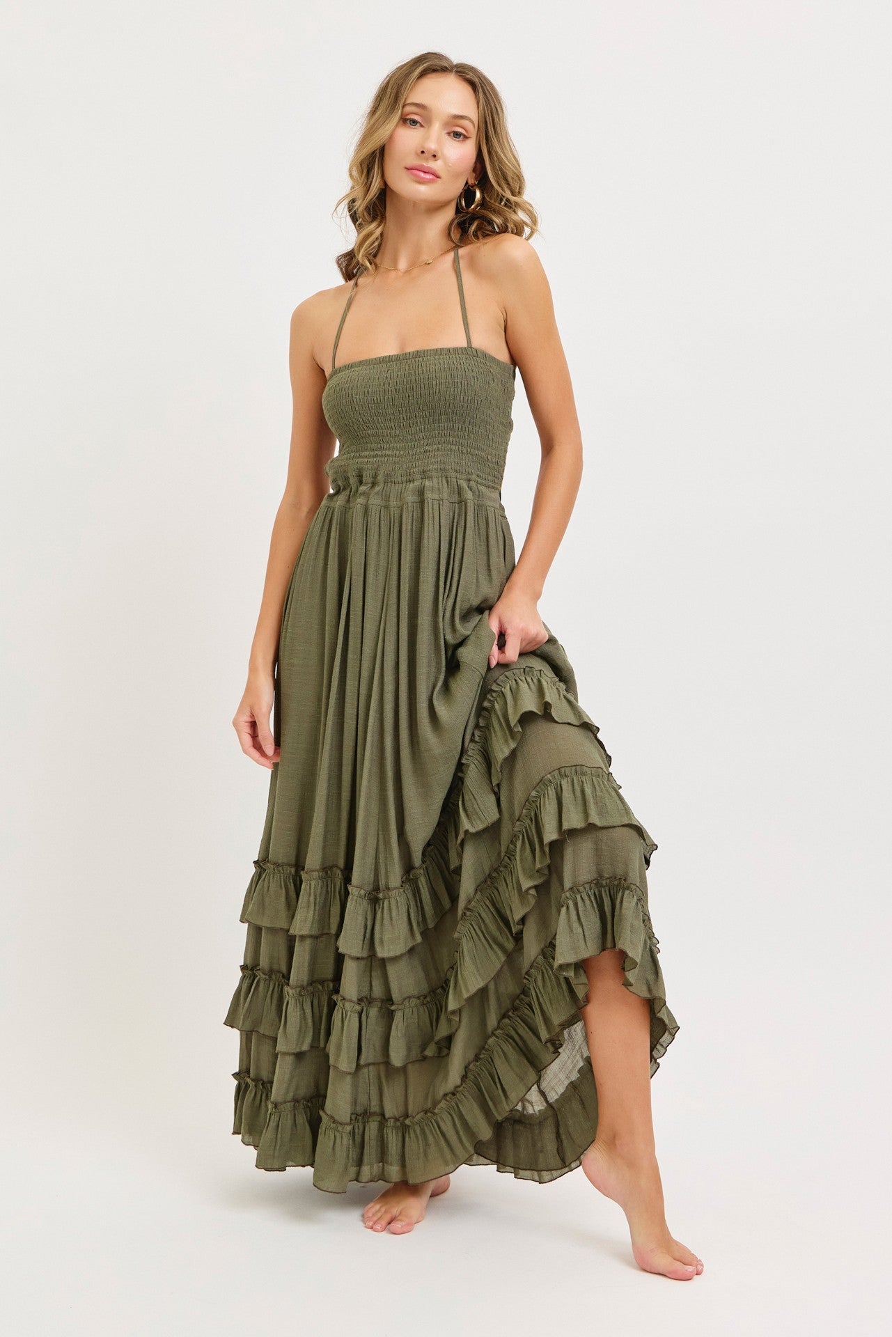 woman wearing an olive green strapless maxi dress with ruffle details and a smocked bodice