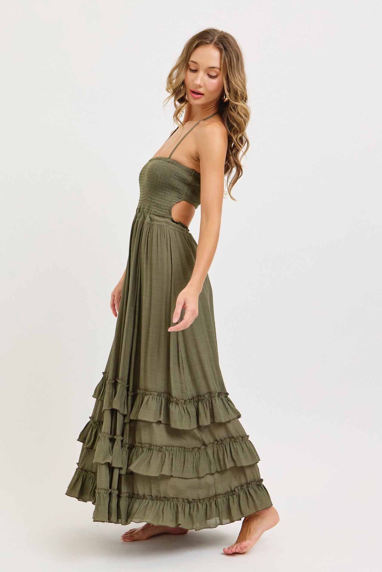 woman wearing a dark green maxi dress with a smocked bodice and ruffled tiers, standing in profile