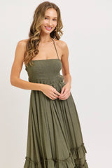woman wearing an olive green smocked sundress with ruffled hem and adjustable straps