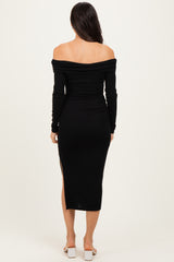 woman wearing a black off-the-shoulder long sleeve dress with a slit, view from the back