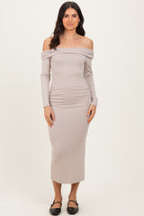 woman wearing a taupe off-the-shoulder long sleeve midi dress with ruched sides and black slip-on shoes