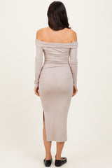 woman wearing a beige off-the-shoulder midi dress with a slit and long sleeves, viewed from the back