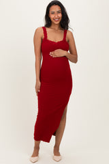 woman wearing a red maternity dress with lace details and a slit, holding her baby bump