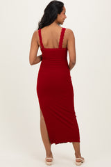 woman wearing a red maternity midi dress with lace straps and a side slit, showing her baby bump from the back