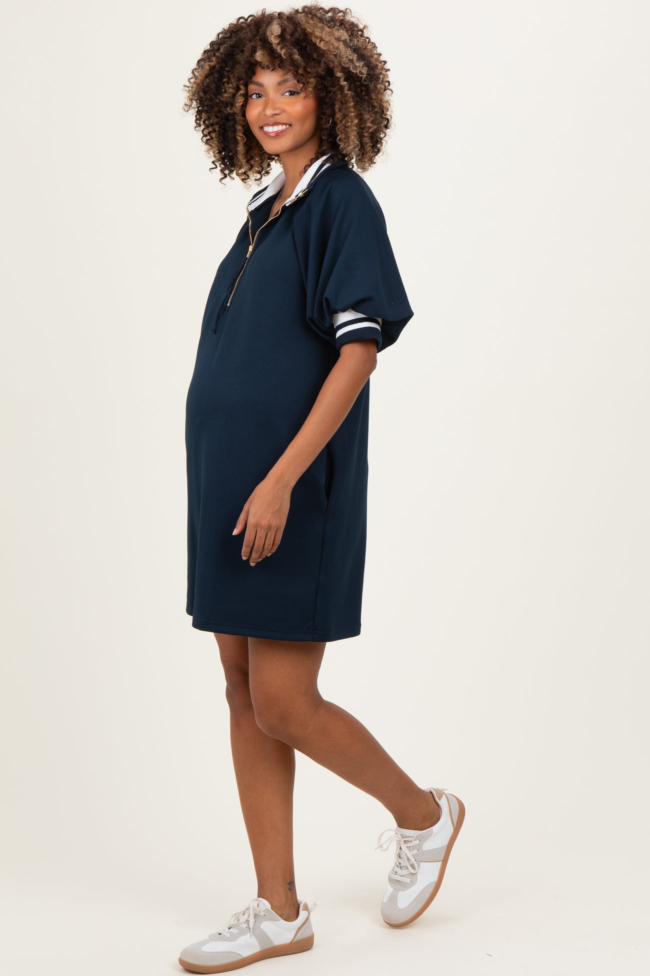 woman wearing a navy maternity polo dress with a zip neck and short sleeves, showcasing her baby bump