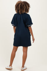 woman wearing a navy blue maternity dress with puff sleeves, shown from the back, paired with white sneakers