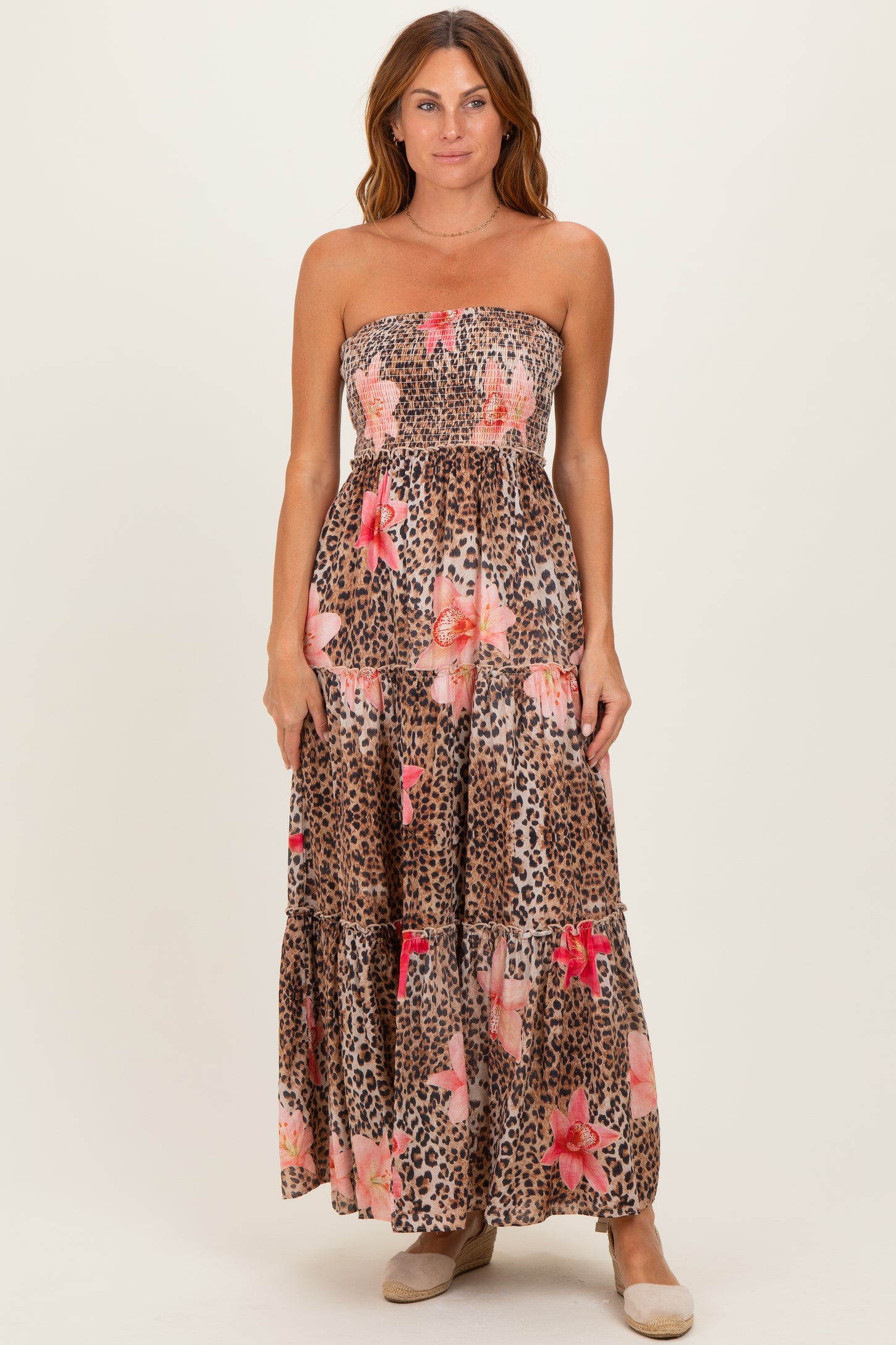 woman wearing a strapless maxi dress with a leopard print and floral design in brown and pink tones