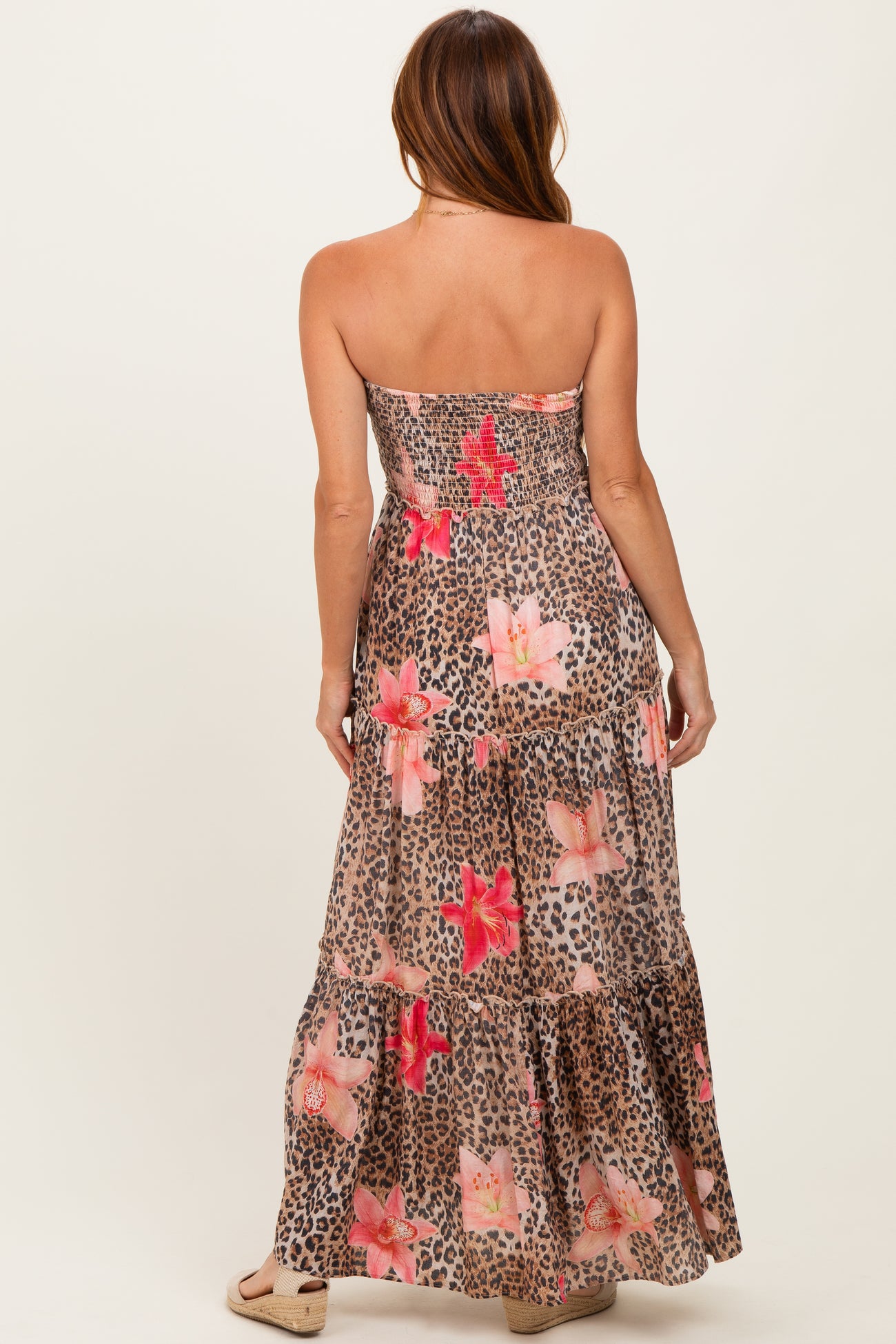 woman wearing a strapless maxi dress with a floral and leopard print pattern, showing the back design