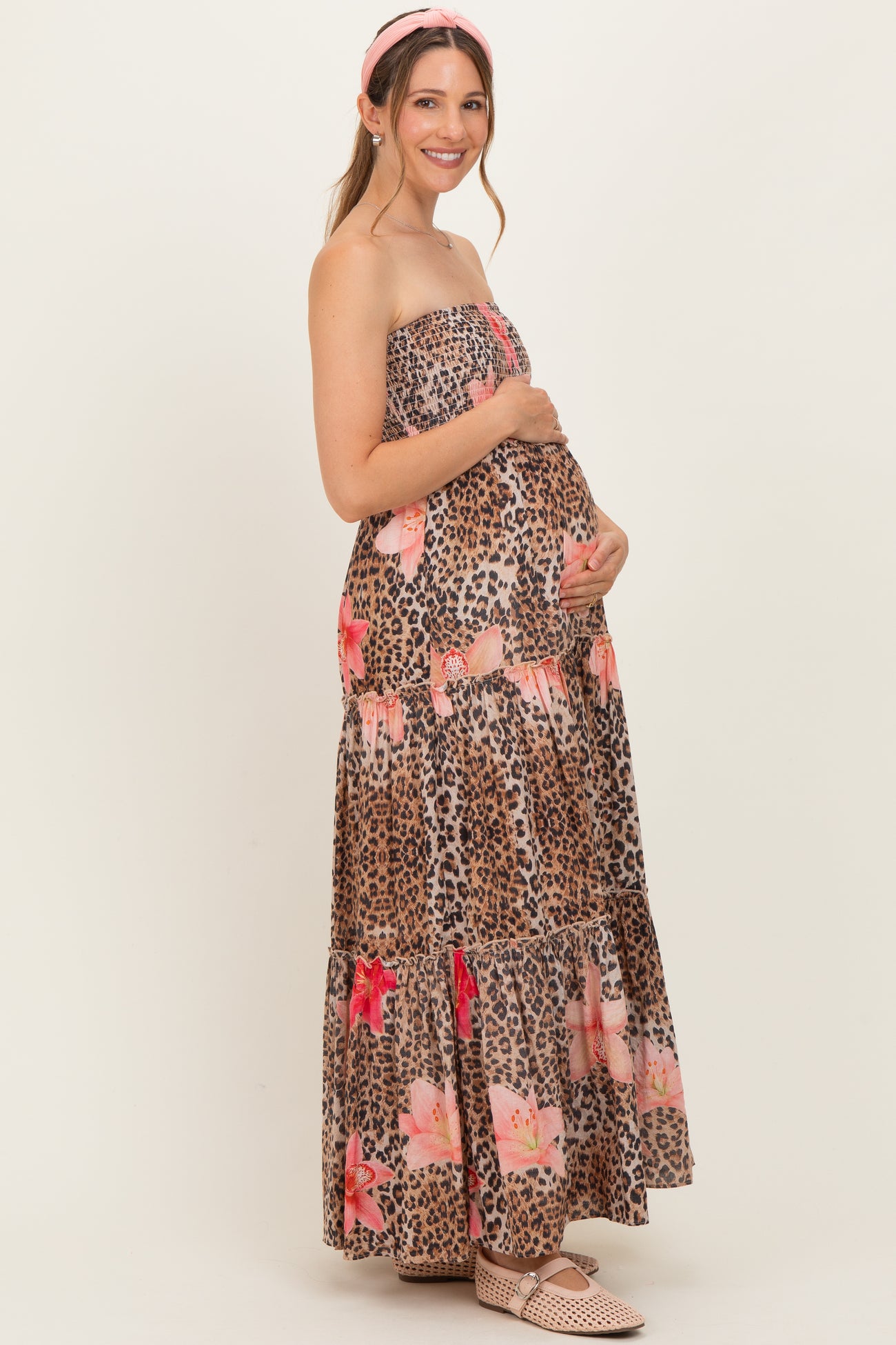 woman wearing a strapless leopard print maxi dress with floral details and holding her baby bump