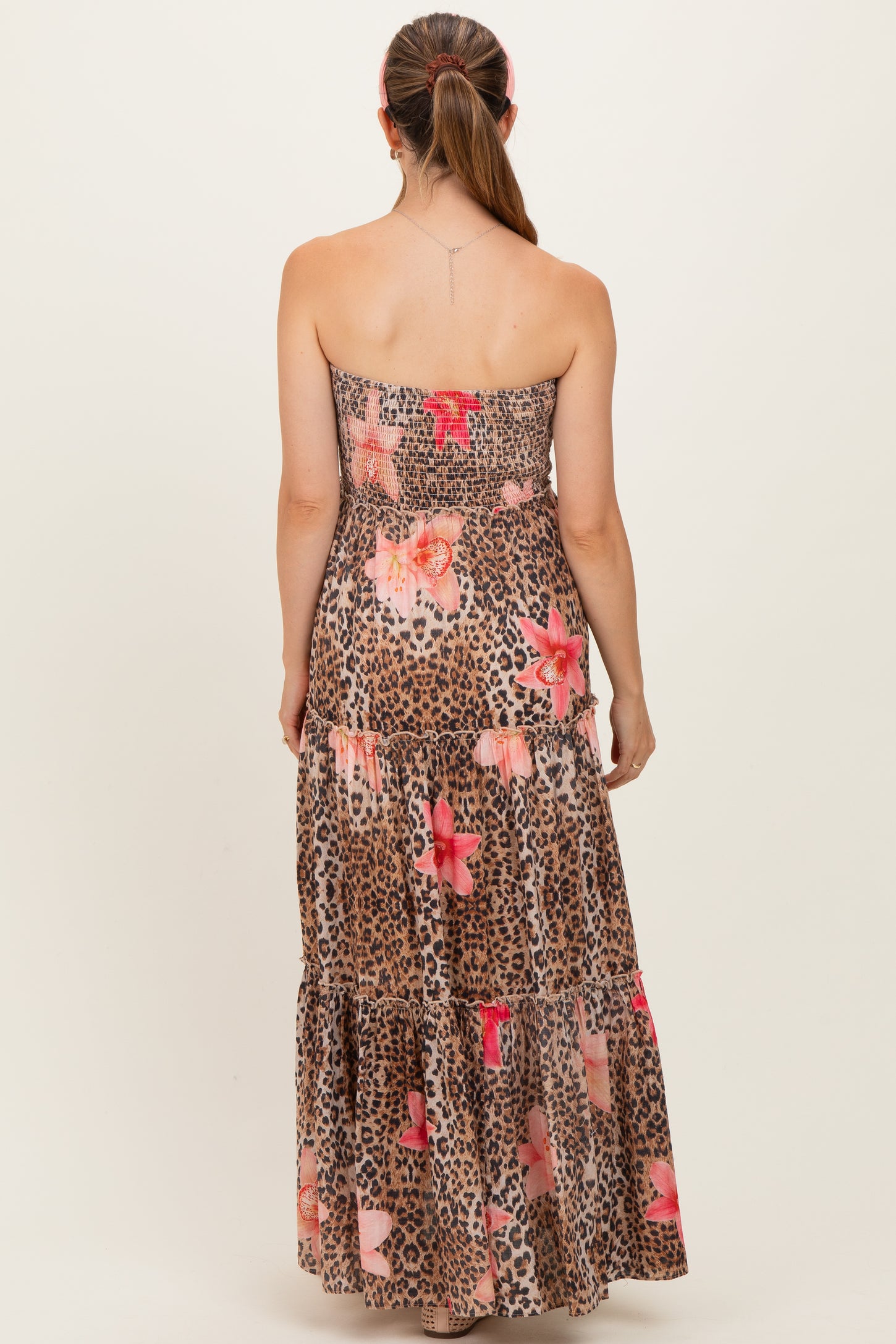 woman wearing a strapless leopard and floral print maternity maxi dress with a tiered skirt from the back