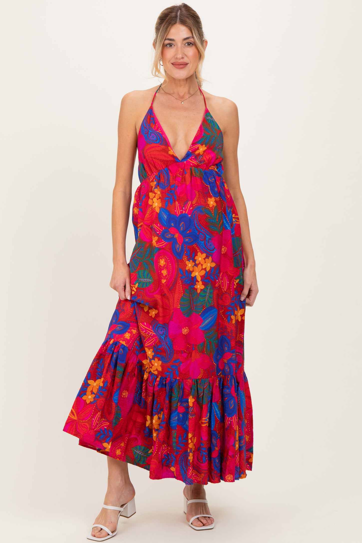woman wearing a vibrant pink floral maternity maxi dress with a deep v-neck and ruffled hem