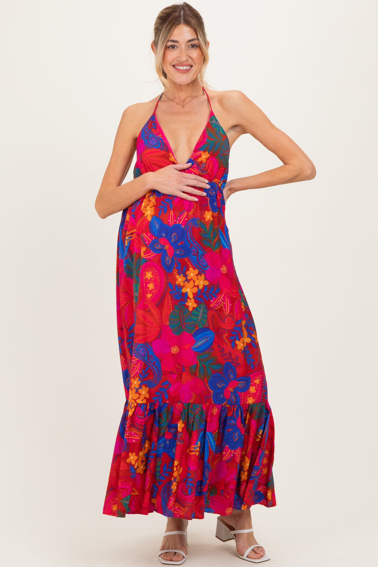 woman wearing a vibrant floral maternity maxi dress with a halter neckline and a visible baby bump